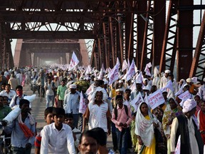 Hindu pilgrims hold religious flags and walk on a crowded bridge after a stampede on the same bridge on the outskirts of Varanasi, India, Saturday, Oct. 15, 2016. (AP Photo)