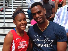 In this May 3, 2014, photo, Trinity Gay, a seventh-grader racing for her Scott County High School team, poses for a photo with her father Tyson Gay, after she won the 100 meters and was part of the winning 4-by-100 and 4-by-200 relays at the meet in Georgetown, Ky. The 15-year-old daughter of Olympic sprinter Tyson Gay was fatally shot in the neck, authorities and the athlete's agent said Sunday, Oct. 16, 2016, and police have arrested a man in connection with the shooting. (Mark Maloney/Lexington Herald-Leader via AP)