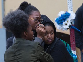 Leslian Warner, centre, and friends of Jarryl Hagley mourn Monday October 17, 2016 outside the West Rd. Pizza Pizza where he was shot and killed early Sunday. (Craig Robertson/Toronto Sun)