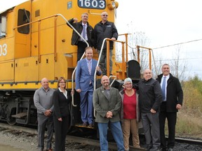 Members of Town Council, community members and ON executives pose with Paul Lefebvre on one of the Ontario Northland engines after the infrastructure announcement made in Cochrane.