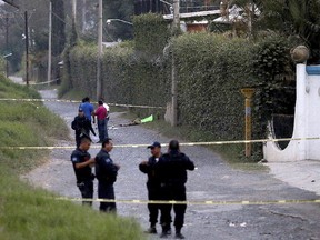 Police secure the area where six people were found alive with their hands cut off, along with another person who was killed, in the background, in Tlaquepaque on the outskirts of Guadalajara, Mexico, Tuesday, Oct. 18, 2016. (AP Photo/Fernando Carranza)