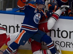 Oilers forward Anton Lander crashes into the boards with Hurricanes Jakub Nakladal during Tuesday's game at Rogers Place. (Greg Southam)