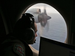 In this March 22, 2014 file photo, flight officer Rayan Gharazeddine scans the water in the southern Indian Ocean off Australia from a Royal Australian Air Force AP-3C Orion during a search for the missing Malaysia Airlines Flight MH370. A ship involved with the deep-sea sonar search for missing Malaysia Airlines Flight 370 is being fitted with equipment to examine several sonar contacts of interest on the remote seabed west of Australia, the Australian Transport Safety Bureau said on Wednesday, Oct. 19, 2016. (AP Photo/Rob Griffith, File)