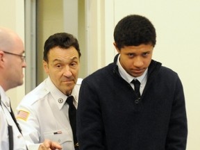 Phillip Chism, 14, from Danvers, Mass., is lead into the court room at his arraignment in Salem Superior Court, Wednesday, Dec. 4, 2013, in Salem, Mass. The family of Colleen Ritzer, the teacher Chism was convicted of killing, is suing the town where she died, the school system and a cleaning company whose workers washed away potential evidence. (AP Photo/The Eagle-Tribune, Paul Bilodeau, Pool)
