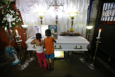 In this Sept. 8, 2016 photo, children look at the body of alleged drug user Marcelo Salvador at their house in Las Pinas, south of Manila, Philippines. Drug dealers and drug addicts, were being shot by police or slain by unidentified gunmen in mysterious, gangland-style murders that were taking place at night. Salvador became a victim, the casualty of a vicious war on drugs that has claimed thousands of lives as part of a campaign by Philippine President Rodrigo Duterte. (AP Photo/Aaron Favila)