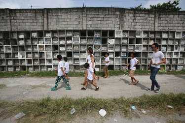 In this Sept. 14, 2016 photo, family and friends walk beside apartment-type tombs as they attend the funeral of alleged drug user Marcelo Salvador at a public cemetery in Las Pinas, south of Manila, Philippines. Drug dealers and drug addicts, were being shot by police or slain by unidentified gunmen in mysterious, gangland-style murders that were taking place at night. Salvador became a victim, the casualty of a vicious war on drugs that has claimed thousands of lives as part of a campaign by Philippine President Rodrigo Duterte. (AP Photo/Aaron Favila)