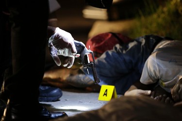 In this Sept. 6, 2016 photo, policemen check the gun recovered from one of two unidentified drug suspects after they were shot dead by police as they tried to evade a checkpoint in Quezon city, north of Manila, Philippines. Bodies had begun turning up in cities all over the Philippines ever since President Rodrigo Duterte launched a controversial war on drugs this year. Drug dealers and drug addicts, were being shot by police or slain by unidentified gunmen in mysterious, gangland-style murders that were taking place at night. (AP Photo/Aaron Favila)