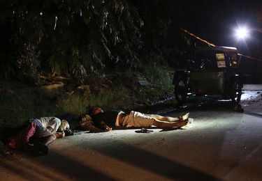 In this Sept. 6, 2016 photo, two unidentified drug suspects lie on the ground after being shot by police as they tried to evade a checkpoint in Quezon city, north of Manila, Philippines. Bodies had begun turning up in cities all over the Philippines ever since President Rodrigo Duterte launched a controversial war on drugs this year. Drug dealers and drug addicts, were being shot by police or slain by unidentified gunmen in mysterious, gangland-style murders that were taking place at night. (AP Photo/Aaron Favila)