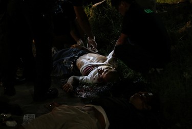 In this Sept. 6, 2016 photo, police inspect one of two unidentified drug suspects after being shot by police as they tried to evade a checkpoint in Quezon city, north of Manila, Philippines. Bodies had begun turning up in cities all over the Philippines ever since President Rodrigo Duterte launched a controversial war on drugs this year. Drug dealers and drug addicts, were being shot by police or slain by unidentified gunmen in mysterious, gangland-style murders that were taking place at night. (AP Photo/Aaron Favila)
