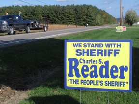 In this Tuesday, Oct. 18, 2016 photo, a truck passes a sign for the election of Pike County Sheriff Charles Reader in Waverly, Ohio. The still-unsolved killing of eight members of the Rhoden family, an investigation overseen by Reader and the Ohio Attorney General's Office, has become an election issue for many voters in the rural southern Ohio county. (AP Photo/Andrew Welsh-Huggins)