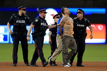 A fan is apprehended by the Police after running on the field in the ninth inning during game five of the American League Championship Series between the Toronto Blue Jays and the Cleveland Indians at Rogers Centre on October 19, 2016 in Toronto, Canada. (Photo by Vaughn Ridley/Getty Images)