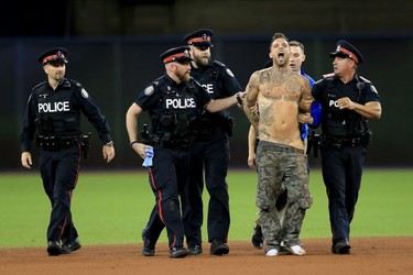 A fan is apprehended by the Police after running on the field in the ninth inning during game five of the American League Championship Series between the Toronto Blue Jays and the Cleveland Indians at Rogers Centre on October 19, 2016 in Toronto, Canada. (Photo by Vaughn Ridley/Getty Images)