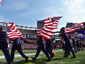 Members of the military carry American flags before a game between the New England Patriots and the Cincinnati Bengals at Gillette Stadium on October 16, 2016 in Foxboro, Massachusetts. (Photo by Billie Weiss/Getty Images)