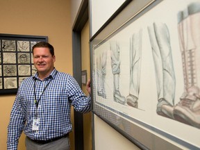 Dr. Charles Nelson, the psychologist in charge of the Operational Stress Injury Program at Parkwood Hospital, stands beside a piece of art depicting footwear worn by soldiers and RCMP officers - the clinic's patients are made up of RCMP and military personnel - in the reception area of the program at Parkwood Hospital in London, Ont. on Thursday October 20, 2016. Craig Glover/The London Free Press/Postmedia Network