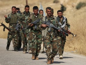 Iraqi Kurdish Peshmerga fighters march down a road in Nawran village, some 10km north east of Mosul, on Oct. 20.