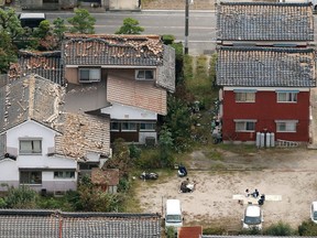 Roof tiles of houses loose as residents sit outside after a powerful earthquake hit Kurayoshi, Tottori prefecture, western Japan, Friday, Oct. 21, 2016. The quake occurred in the prefecture on the Sea of Japan, collapsing houses and causing power outages Friday afternoon, but apparently caused no widespread damage. (Kyodo News via AP)