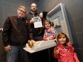 Dad Club London members Jeremy McCall and Brett Roberts, left, are joined by Roberts' daughters Abby, 2, and Miya, 3, as they show the newly installed baby changing table in the men's washroom at Dolcetto in London, Ont. on Thursday October 20, 2016. The club is asking establishments across London to follow the lead and install baby changing tables in men's washrooms. Craig Glover/The London Free Press/Postmedia Network
