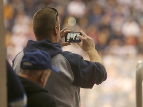 A hockey fan stands to shoot video with his phone at Heritage Classic practices.