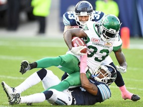 Saskatchewan Roughriders' Joe McKnight is tackled by Toronto Argonauts' Aaron Berry and Jamal Campbell during first half CFL action in Toronto on Oct. 15, 2016. (THE CANADIAN PRESS/Frank Gunn)