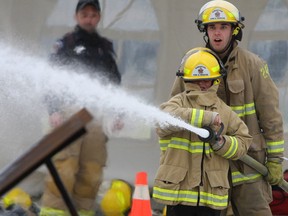 Liam McKillen puts out a simulated car fire with the help of firefighter Caelen Martin at the Kingston Fire and Rescue open house in support of the United Way at their training centre in Kingston, Ont. on Saturday October 22, 2016. Steph Crosier/Kingston Whig-Standard/Postmedia Network