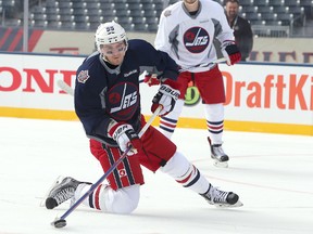 WINNIPEG, MANITOBA - OCTOBER 22: Mark Scheifele, left, of the Winnipeg Jets shoots from his knees during practice in preparation for the 2016 Tim Hortons NHL Heritage Classic alumni hockey game on October 22, 2016 at Investors Group Field in Winnipeg, Manitoba.