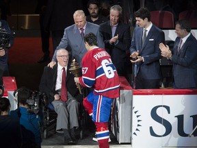 Montreal Canadiens captain Max Pacioretty is presented with the flame from Senator Jacques Demers during a pre-game torch ceremony for the team's home opener Tuesday, October 18, 2016 in Montreal. (THE CANADIAN PRESS/Paul Chiasson)