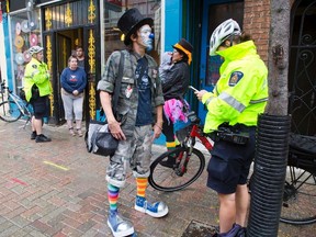 "Buttons Blammo" (AKA Brian Currie) is questioned by constable Joyce Spruyt following a complaint that he vandalize City Lights Bookshop in London, Ont. on Thursday October 20, 2016. Blammo defaced the store to protest a "no clowns allowed" sign hanging in the store front window that he claimed was racist againts clowns. He was let go with a warning. (Derek Ruttan/Postmedia Network)