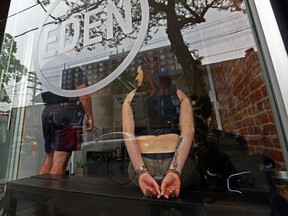 A woman sits in handcuffs after Toronto Police raided Eden on Queen St during a series of raids on marijuana dispensaries in May, 2016. (DAVE ABEL, Toronto Sun)