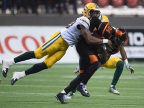 Deon Lacey tackles Lions slotback Manny Arecenaux during Saturday's game in Vancouver. (The Canadian Press)
