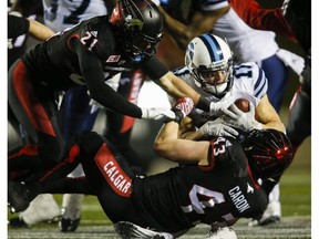 Toronto Argonauts' Devon Wylie, centre, is brought down by Calgary Stampeders Adam Berger, left, and Max Caron during second-half CFL action in Calgary on, Oct. 21. (Jeff McIntosh/The Canadian Press)