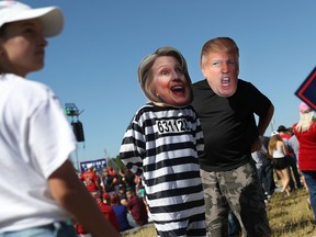 People wearing Democratic presidential candidate Hillary Clinton and Republican presidential candidate Donald Trump masks wait for his arrival at campaign rally at the Collier County Fairgrounds on October 23, 2016 in Naples, Florida. (Joe Raedle/Getty Images)