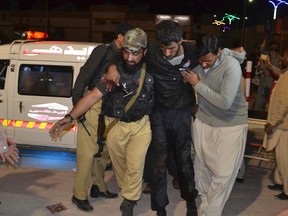A Pakistani volunteer and a police officer rush an injured person to a hospital in Quetta, Pakistan, Monday, Oct. 24, 2016. (AP Photo/Arshad Butt)