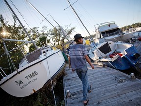 Chris Hinds walks between boats pushed up amongst the twisted docks at Palmetto Bay Marina damaged by Hurricane Matthew in Hilton Head, S.C., Sunday, Oct. 9, 2016. (AP Photo/David Goldman)