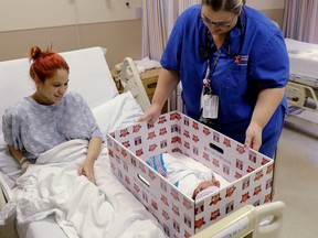 In this May 6, 2016, file photo, Keyshla Rivera smiles at her newborn son Jesus as registered nurse Christine Weick demonstrates a baby box before her discharge from Temple University Hospital in Philadelphia on Friday, May 6, 2016. (AP Photo/Matt Rourke, File)