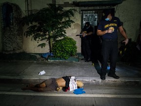 Police examine the body of a summary execution victim with his hands tied around his back and his head wrapped in packaging tape on October 1, 2016 in Manila, Philippines. The Duterte administration shifted to the next phase on its war on drugs after the first 100 days of President Rodrigo Duterte as over 3,700 people have been killed while more than 700,000 drug dependents surrendered to authorities. According to reports, Duterte received an "excellent" rating for his war on drugs during a recent opinion, with 84 percent of Filipinos respondents said they are satisfied with the drug crackdown. (Photo by Dondi Tawatao/Getty Images)