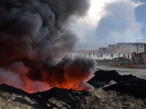 Children play football next to an oil field that was set on fire by retreating ISIS fighters ahead of the Mosul offensive, on October 21, 2016 in Qayyarah, Iraq. Several hundred Iraqi families have been made to leave their homes for Mosul by Islamic State fighters as the UN warns they could be used as human shields. ISIS have attacked Kirkuk today as Kurdish and Iraqi forces, backed by a coalition including Britain and the U.S.A continue their offensive to retake Iraq's second largest city of Mosul. (Photo by Carl Court/Getty Images)
