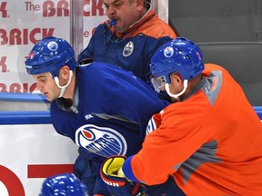 Oilers forward Zack Kassian and defenceman Andrej Sekera push head coach Todd McLellan against the boards during an Oilers practice drill at the Rogers Place community arena Tuesday. (Ed Kaiser)