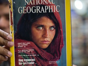 Pakistan's Inam Khan, owner of a book shop shows a copy of a magazine with the photograph of Afghan refugee woman Sharbat Gulla, from his rare collection in Islamabad, Pakistan, Wednesday, Oct. 26, 2016. A Pakistani investigator says the police have arrested National Geographic's famed green-eyed 'Afghan Girl' for having a fake Pakistani identity card. Shahid Ilyas from the Federal Investigation Agency, says the police arrested Sharbat Gulla during a raid on Wednesday at a home in Peshawar. (AP Photo/B.K. Bangash)