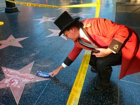 Gregg Donovan, who calls himself the unofficial ambassador of Hollywood, places a sticker for Republican presidential candidate Donald Trump on Trump's vandalized star on the Hollywood Walk of Fame, Wednesday, Oct. 26, 2016 in Los Angeles.(AP Photo/Richard Vogel)