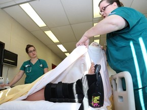 Tim Miller/The Intelligencer 
Nursing student Angela Scatcherd checks the foot of a patient during in a simulation at the Nursing SIM Lab at Loyalist College on Tuesday, October 11, 2016 in Belleville. The simulation was part of a funding announcement for the college's Health and Wellness Centre.