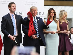 Republican presidential candidate Donald Trump, together with his family, from left, Eric Trump, Melania Trump and Tiffany Trump, waves part of a ribbon after cutting the ribbon during the grand opening of Trump International Hotel in Washington, Wednesday, Oct. 26, 2016. Donald Trump and his children hosted an official ribbon cutting ceremony and press conference to celebrate the grand opening of his new hotel. (AP Photo/Manuel Balce Ceneta)