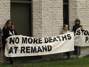 Supporters hold signs during a rally at the Winnipeg Remand Centre regarding deaths in custody on Wed., Oct. 26, 2016.