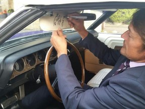Teemu Selanne signs the visor of Pat Kaniuga's 1970 Dodge Challenger, a rare convertible that Selanne also has in his collection.