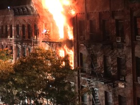 Flames rise from an apartment building fire on the Upper East Side in New York on Thursday, Oct. 27, 2016. The flames quickly spread throughout the building and were shooting out the roof at one point, sending burning embers onto nearby buildings. (Matt Bonaccorso via AP)