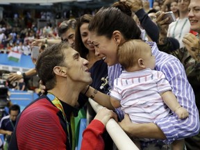 United States' swimmer Michael Phelps celebrates winning his gold medal in the men's 200-meter butterfly with his fiance Nicole Johnson and baby Boomer during the swimming competitions at the 2016 Summer Olympics, in Rio de Janeiro, Brazil. The Arizona Republic reported Oct. 26, 2016, that Phelps and Johnson secretly married on June 13, 2016. (AP Photo/Matt Slocum, File)