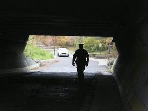 A Peel Regional Police officers walks through the Mississauga underpass where an SUV was found torched after a police chase on Saturday, October 29, 2016. (Veronica Henri/Toronto Sun/Postmedia Network)