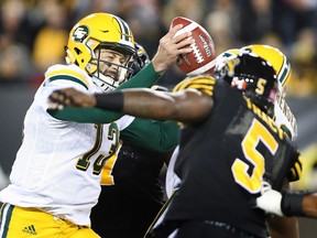 Edmonton Eskimos quarterback Mike Reilly (13) fakes a pass and holds the ball while under pressure from the Hamilton Tiger-Cats defence during the first-half of CFL football action in Hamilton on Friday, October 28, 2016.