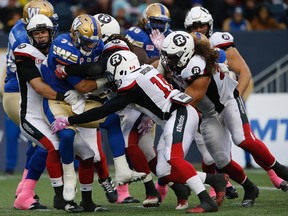 Andrew Harris gets swarmed by Ottawa Redblacks players on Saturday. (CANADIAN PRESS)