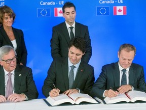 (From L) President of the European Commission Jean-Claude Juncker looks on as Canada's Prime Minister Justin Trudeau (C) and European Council President Donald Tusk sign the Comprehensive Economic and Trade Agreement (CETA), at the European Council in Brussels, on Oct. 30, 2016. (THIERRY MONASSE/AFP/Getty Images)