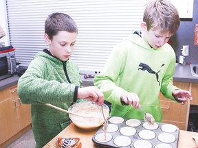 Grade 6 students Logan Gorzitza and Connor Mitchell fill a baking sheet with banana muffin batter during the Vulcan Volunteer program Friday afternoon at the Vulcan Prairieview Elementary School.